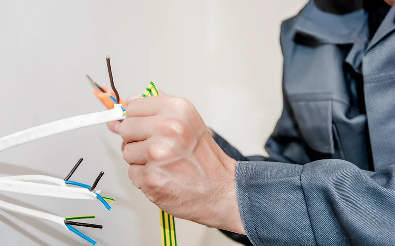 Electrician stripping and terminating cable conductors during a rewire